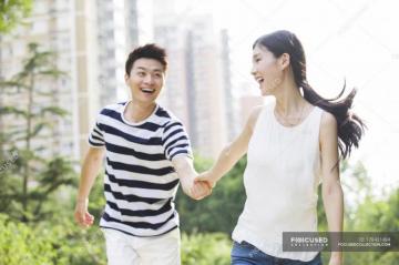 Young Chinese Couple Holding Hands While Walking In Park
