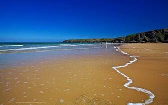 Gentle Surf On Sandy Beach Background Wallpaper