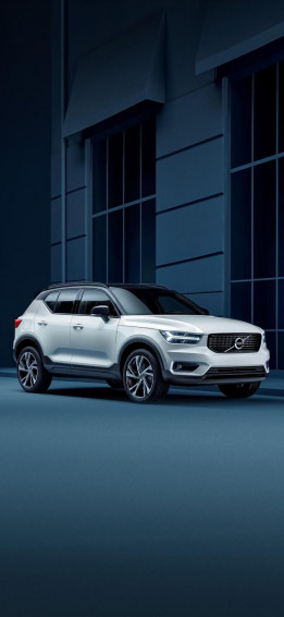White Volvo Suv Parked In Front Of A Building Wallpaper