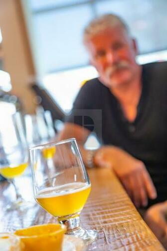 Glass Of Micro Brew Beer On Bar With Handsome Man In Background