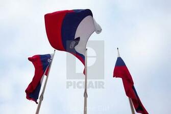 Three Flags Of Slovenia Waiving In The Air With A Cloudy Sky