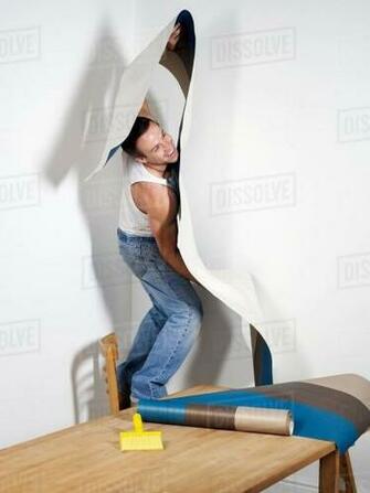 Smiling Man Struggling With Wallpaper Stock Photo Dissolve