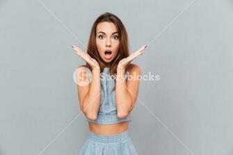 Surprised Shocked Young Woman Standing With Opened Mouth Over Grey