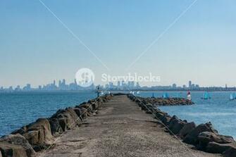 Long Pier Jetty With Sailing Boats And Modern Cityscape On The