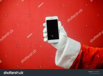 Santa Claus Using Smart Phone On Red Texture Background Closeup