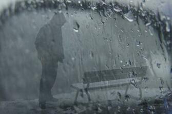 HD Sad Boy Wearing Hood Standing In Rain With Bench Wallpaper Image