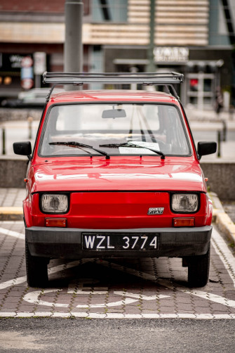 Red Car Parked In Front Of Building During Daytime Photo