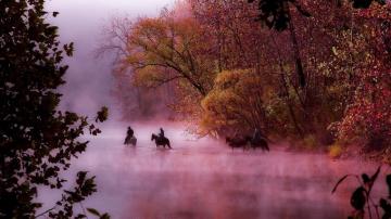 Horses And Riders Crossing The River On A Foggy Morning In