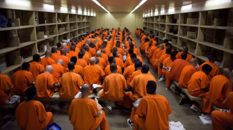 Prison Group Of Prisoners Sitting In Orange Uniforms Background Wallpaper