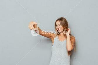 Smiling Young Girl Making Selfie Photo On Smartphone Over Gray