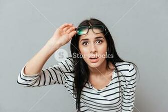 Young Woman Wearing Eyeglasses Shocked Over Grey Background