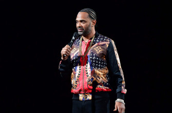 Mike Epps Strikes A Thoughtful Pose Against Textured Grey Wallpaper