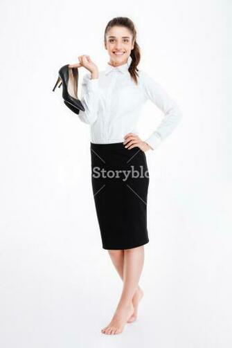 Smiling Lovely Young Businesswoman Standing Barefoot And Holding