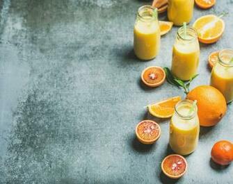 Photos Healthy Yellow Smoothie In Bottles Over Concrete