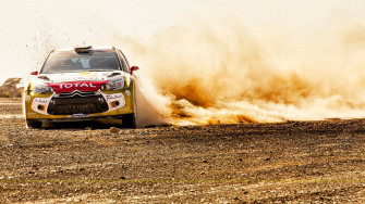 A Rally Car Driving Through Dusty Area Wallpaper