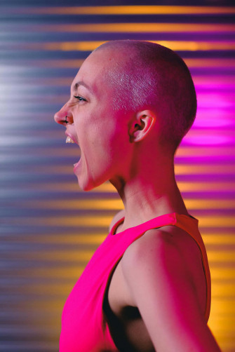 Bald Woman Laughing Against Colorful Wallpaper