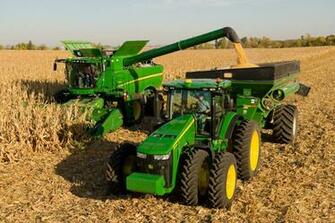Combine Harvesting Corn With The Help Of A Tractor And Loading Bin