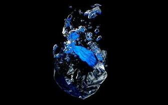 Ice Cube Falling Into Water Against A Black Background