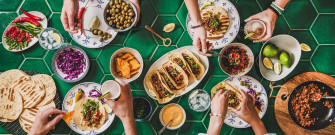 A Group Of People Eating Food On Green Tiled Table Wallpaper