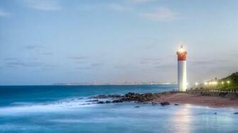 Marvelous Lit Lighthouse With City In The Background Hq Wallpaper