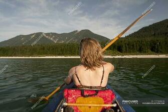 Rear Of Woman Paddling Canoe Over Mountain Range On
