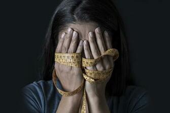 Close Up Hands Wrapped In Tailor Measure Tape Covering Face Of
