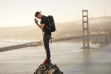 Man In Black T Shirt And Blue Denim Jeans Standing On Rock Near