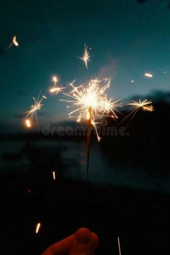 Person Holding Bengal Lights Or Sparklers On A Dark Blurry