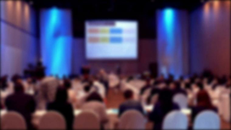 People Sit On Rows Of Chairs In Large Conference Convention Hall