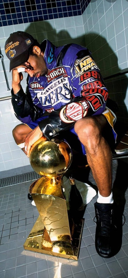 A Man Sitting On Toilet With Trophy Wallpaper