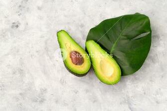 Top Of Halved Avocado And Monstera Leaf On A Gray Background