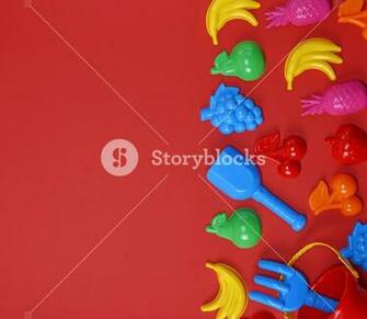 Plastic Childrens Toys In The Form Of Fruit And A Bucket On Red