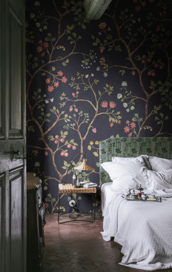 A Moody Bedroom With Skylight Floral Wallpaper An Upholstered Bed Neutral Bedding Woven Stool Lamp Dresser