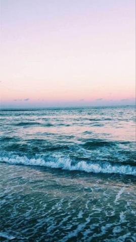 Calm Ocean Waves Rolling To Shore As The Sun Sets Beach