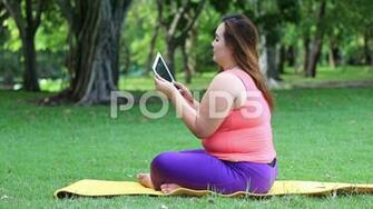 Beautiful Fat Woman Using A Tablet Computer To Relax In The Park