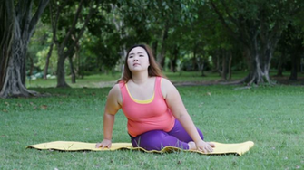 Beautiful Fat Woman Doing Yoga Seat Twist On The Mat In Park
