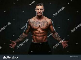 A Muscular Tattooed Man On Dark Background